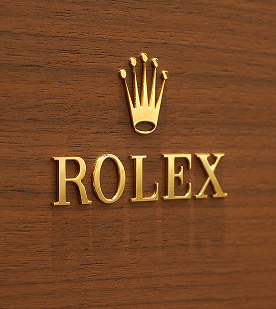 Goldenes Rolex Logo an einer holzvertäfelten Wand